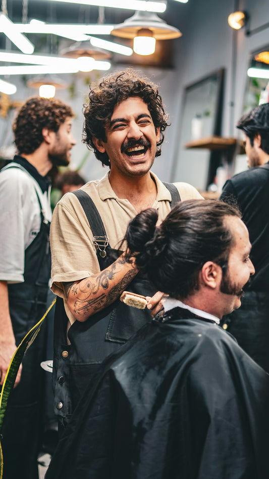 Barber laughs while cutting a client's hair