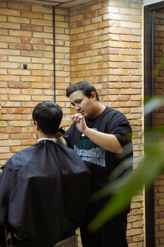 Barber cutting hair with clippers in a salon.
