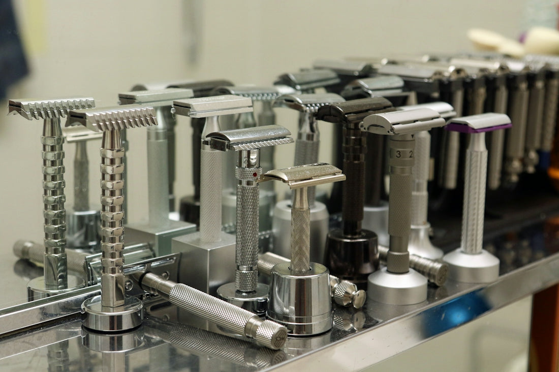 Various metal safety razors displayed on a reflective surface