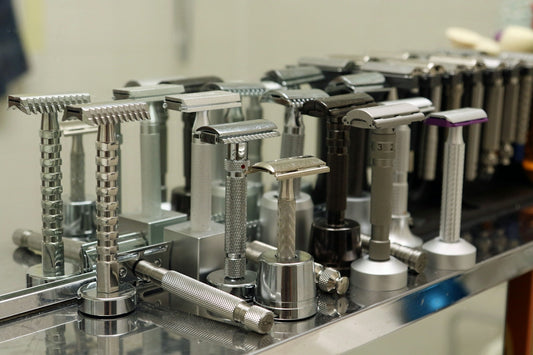 Various metal safety razors displayed on a reflective surface